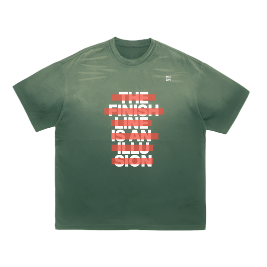 Introducing the UT060 T-Shirt by ODMPOD, a unisex piece in green made from 100% cotton. It showcases bold white text on the front, partially covered with red lines, that reads "THE FINISH LINE IS AN ILLUSION." This shirt is ideal for achieving a street casual look.