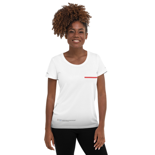 A person with curly brown hair is smiling and wearing a fitted white sports mesh WT003 ▪ T-shirt by Layers Supply with a small red line on the left side of the chest. The person, dressed in black pants, stands against a plain white background, showcasing the moisture management capabilities of their outfit.