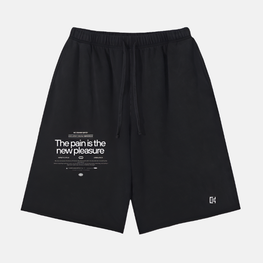 The Scattered Edge Vintage Washed Short Pants by ODMPOD are displayed. These shorts feature a drawstring waist and come in a black stone wash. The left leg is adorned with white text that reads "The pain is the new pleasure," and there's a small logo near the bottom hem, making them perfect for casual wear.