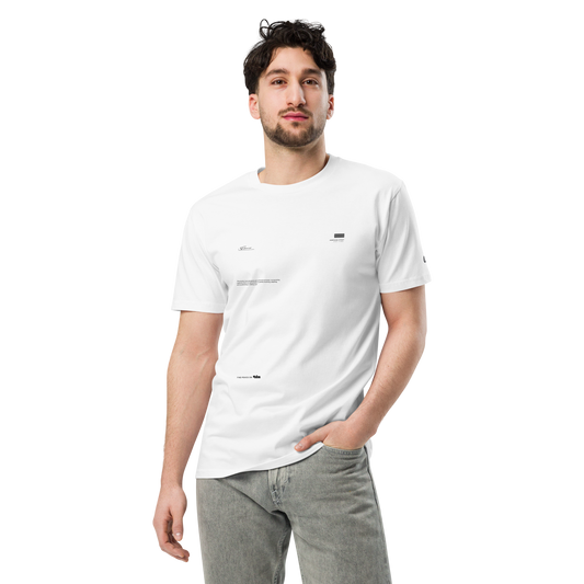 A man with dark hair and a beard stands confidently, wearing a premium white UT047 ▪ T-Shirt from C3 made from 100% combed cotton with small black text details and light grey jeans. His left hand is in his pocket, and he is looking directly at the camera against a plain black background.