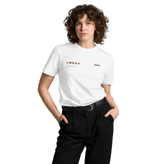 A person with curly hair stands with hands in their pockets, wearing a UT048 ▪ T-Shirt from C3 made from 100% combed cotton. The white T-shirt features small colorful graphics on the upper chest and is paired with black regular fit pants. The background is plain and black.