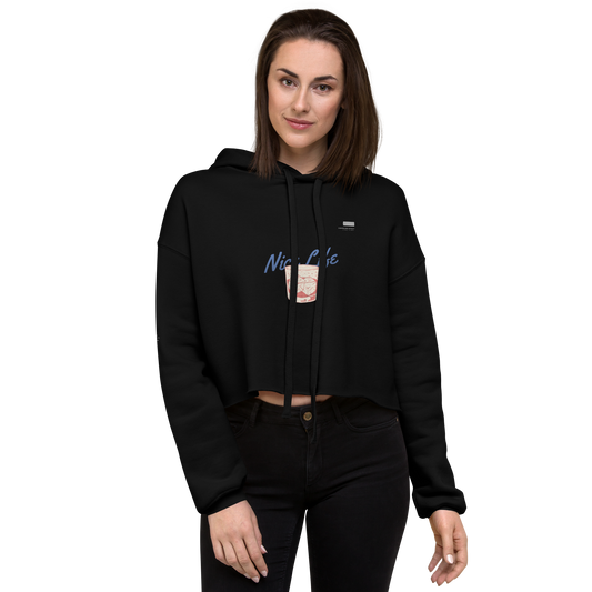 A person with long dark hair is standing and smiling at the camera. They are wearing a WH001 ▪ Crop Hoodie by Layers Supply, featuring a trendy raw hem and a graphic on its cropped body. The background is plain and white.